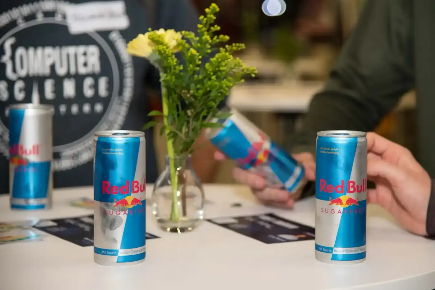 Red Bull Sugar Free Dosen auf einem Tisch bei einem Firmenevent an der TU Wien mit Blumendekor und Eventfotograf im Hintergru