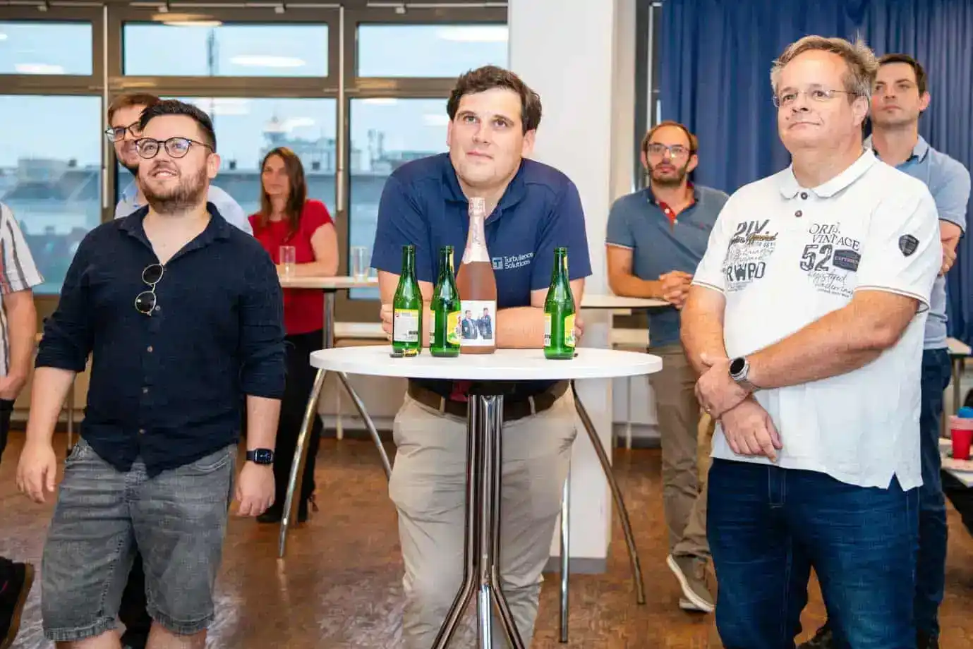 Eventfotograf dokumentiert Diskussionsrunde mit mehreren Teilnehmern um einen Tisch mit Getränken in modernem Büro mit Stadtb