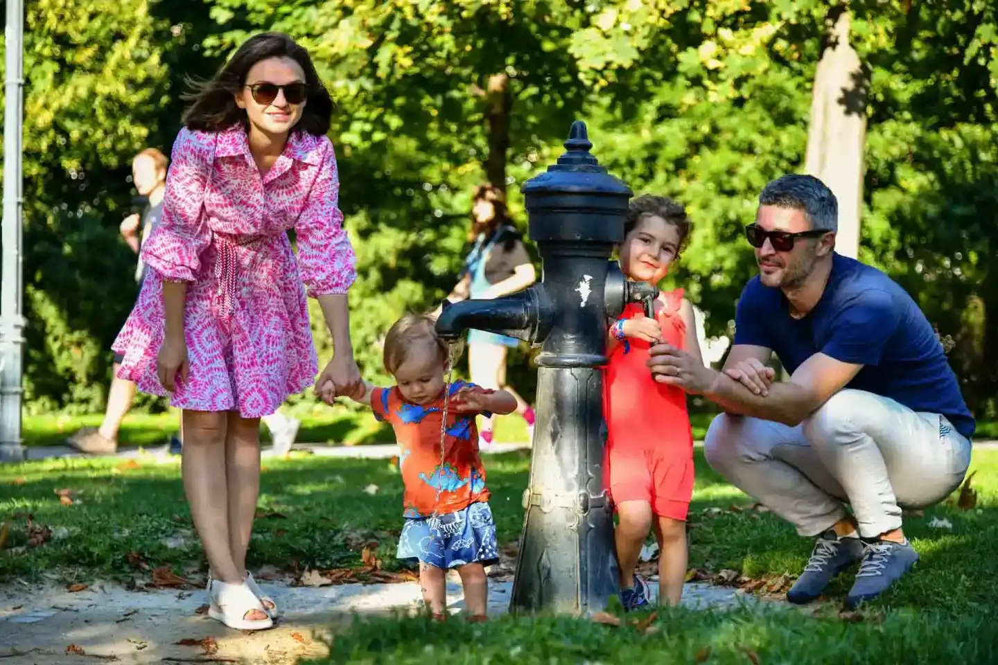 Familie mit zwei kleinen Kindern an einer Wasserpumpe im Park - Familienfotografie Wien