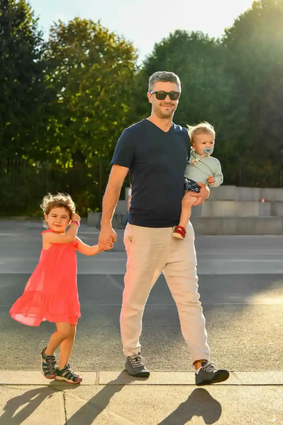 Vater mit zwei kleinen Kindern auf sonniger Terrasse, Familienfotografie Wien