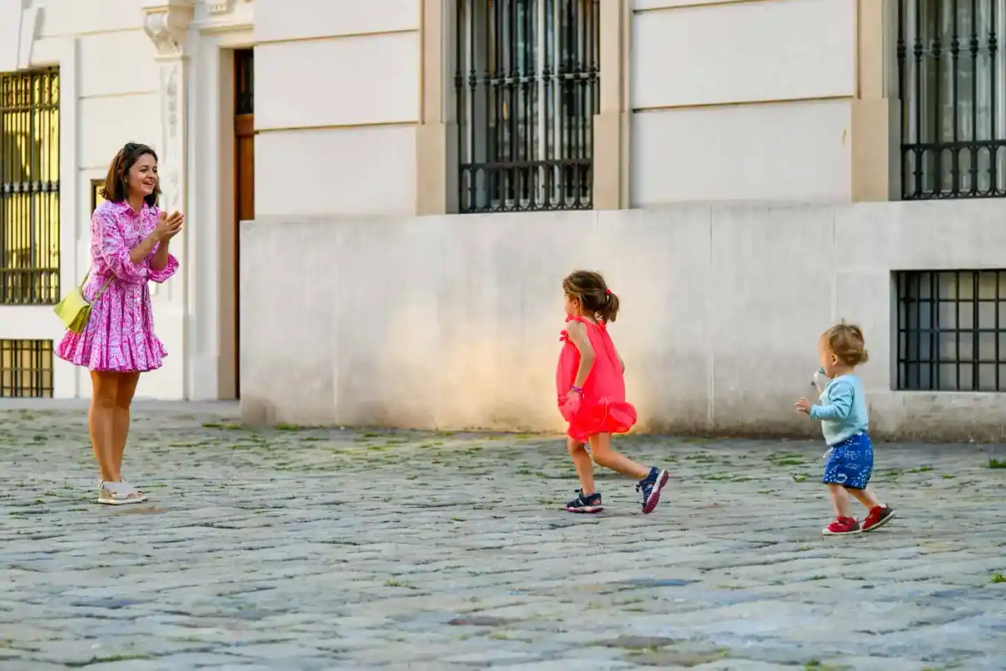 Mutter mit zwei kleinen Kindern beim Spielen in einem Hof, professionelle Familienfotografie Wien