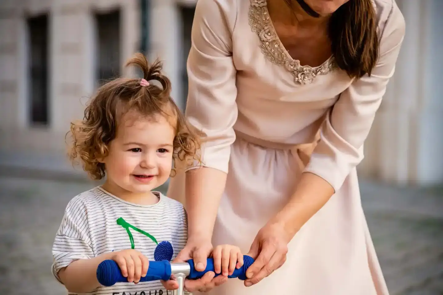Mutter mit kleiner Tochter mit lockigem Haar hält blaues Spielzeug-Mikrofon, professionelle Familienfotografie Wien