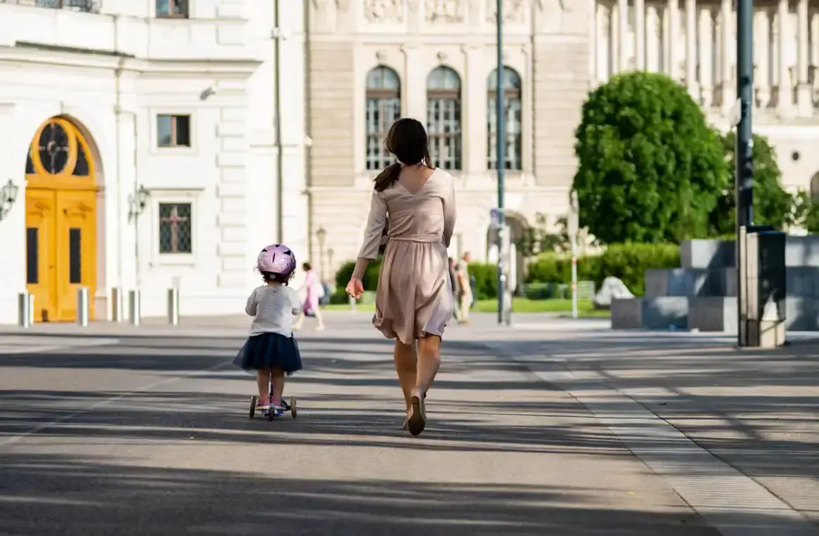 Mutter und kleines Kind auf Roller in Wien vor historischen Gebäuden - Familienfotografie Wien