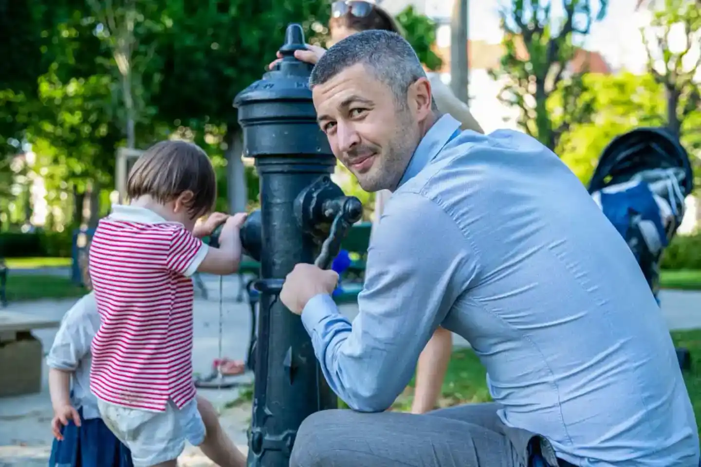 Vater und Sohn spielen zusammen an einem Brunnen im Park – ein schönes Moment der Familienfotografie Wien