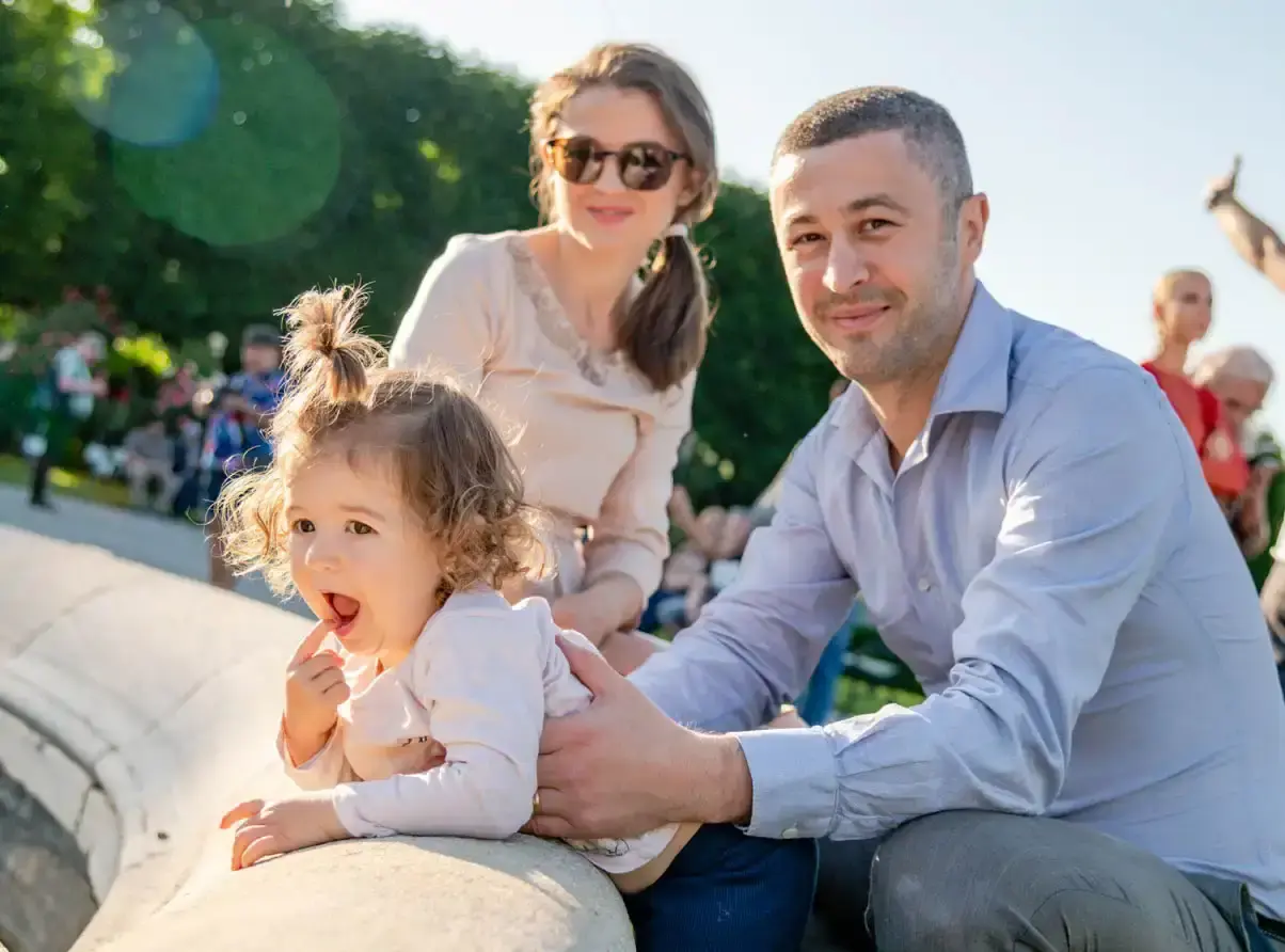 Glückliche Familie mit kleinem Kind sitzt zusammen im Park – professionelle Familienfotografie Wien