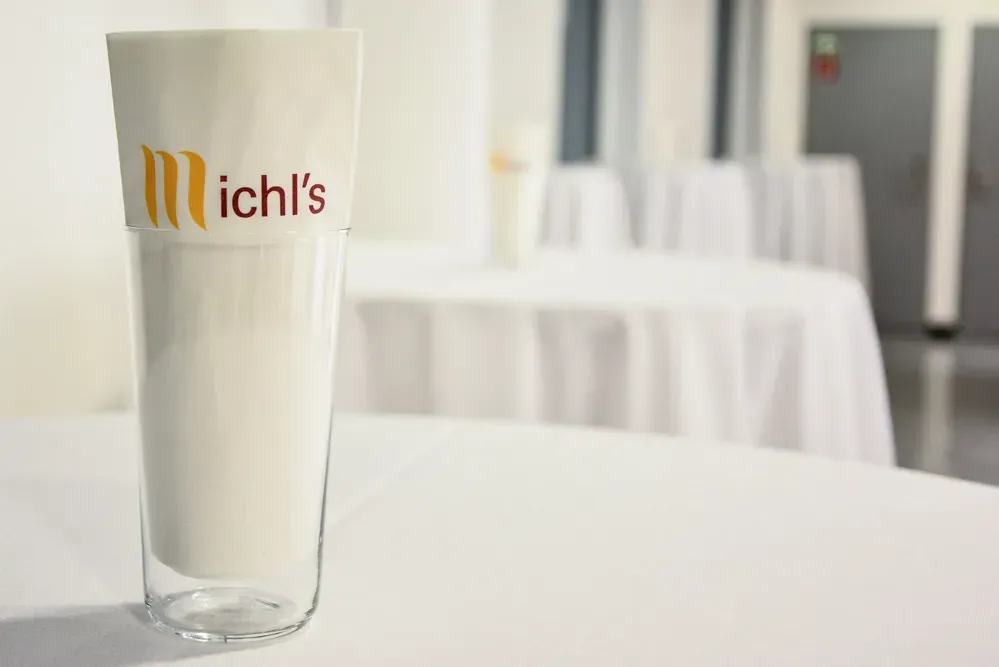 Elegantes Milchglas mit Michl's Logo auf weißem Tisch in modernem Restaurant – professionelle Foodfotografie Wien