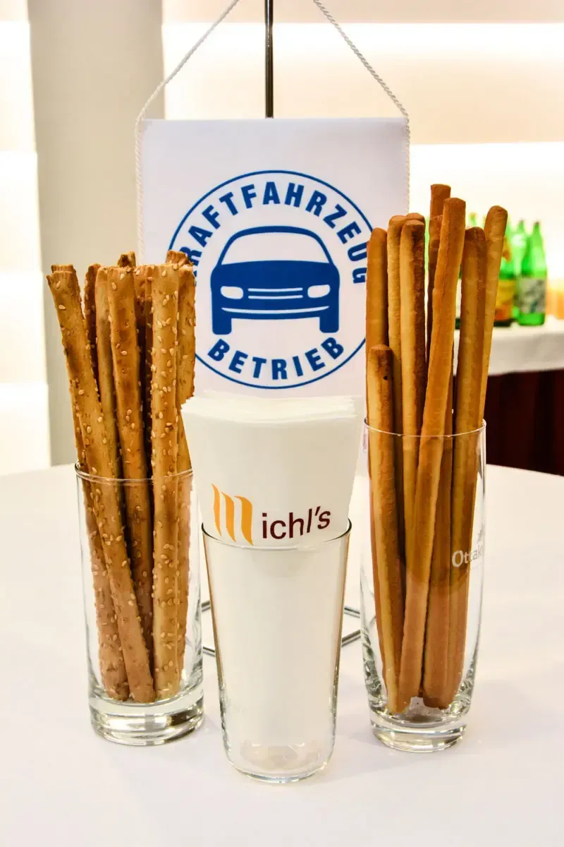 Zwei Gläser mit Salzstangen und Brezelstangen neben einer Kaffeefahrten-Betrieb Schild – professionelle Foodfotografie Wien