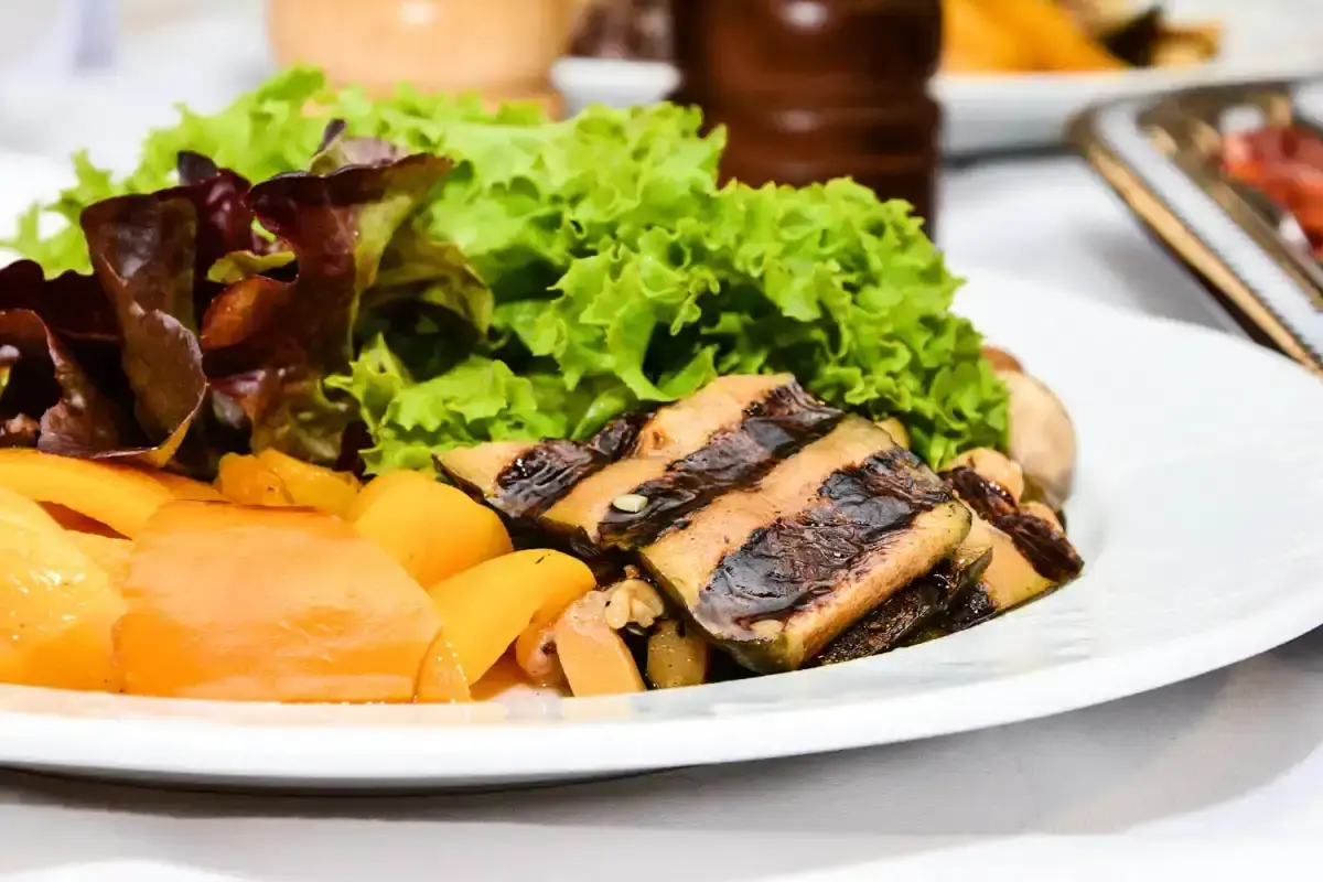Gegrilltes Steak mit Grillmarks auf weißem Teller, garniert mit grünem Salat und gebratenen Kartoffeln - Food Fotografie Wien