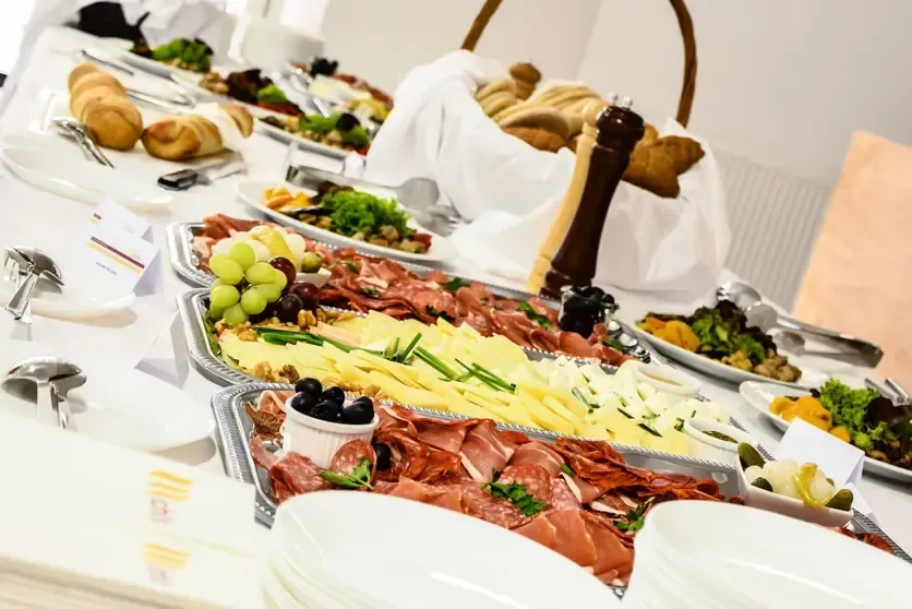 Elegante Charcuterie Board mit Prosciutto, Käse, grünen Trauben und Oliven auf weißem Tisch - professionelle Foodfotografie W