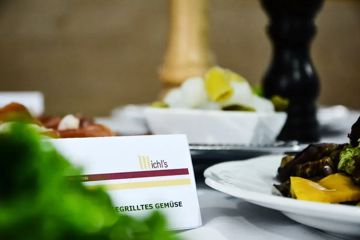 Elegante Restaurantaufnahme mit Ichls Schild, gegrilltem Gemüse auf weißem Teller und fine dining Tischdekoration