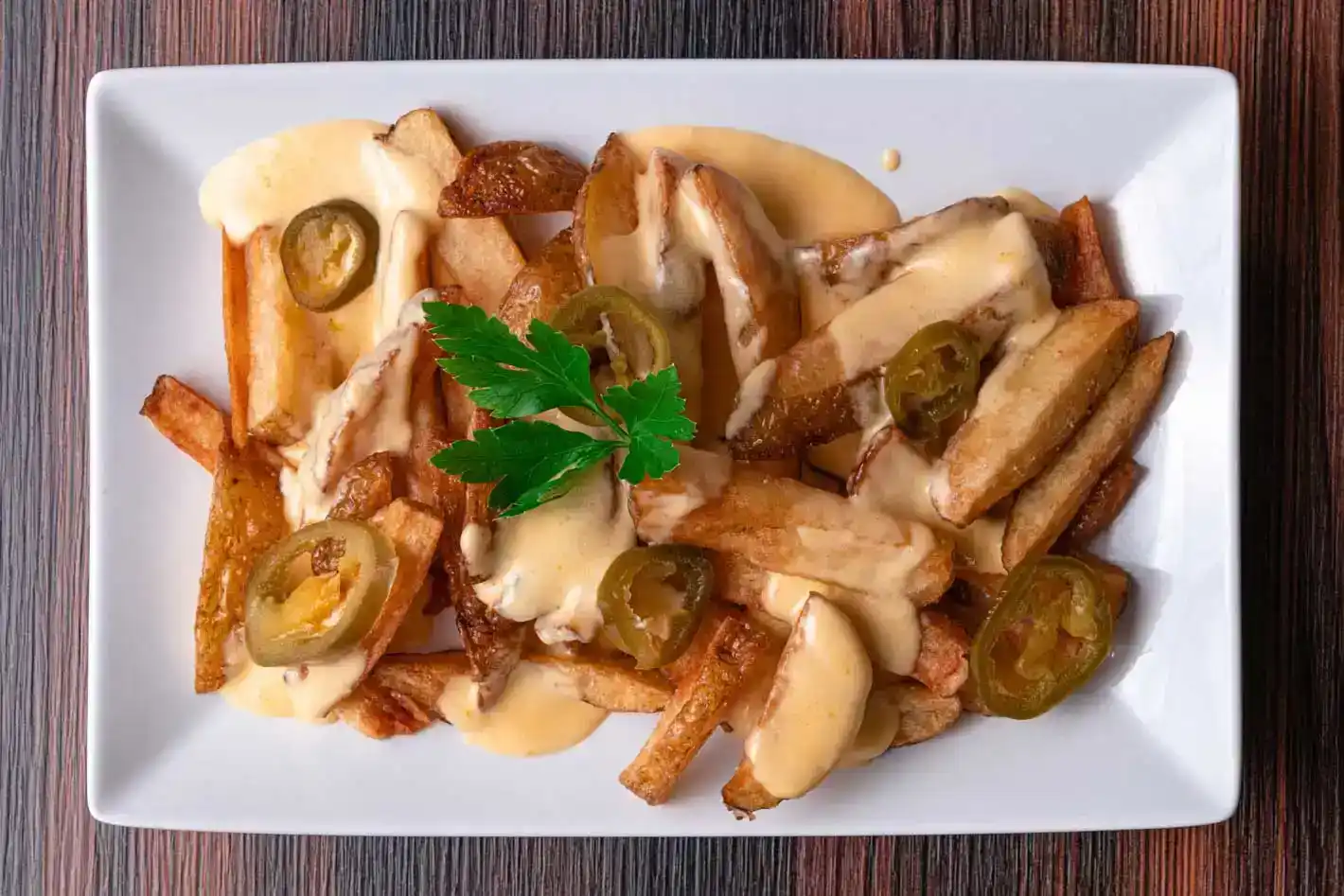 Gourmet Cheeseburger mit Jalapenos und Pommes Frites auf weißem Teller - Food Fotografie Wien