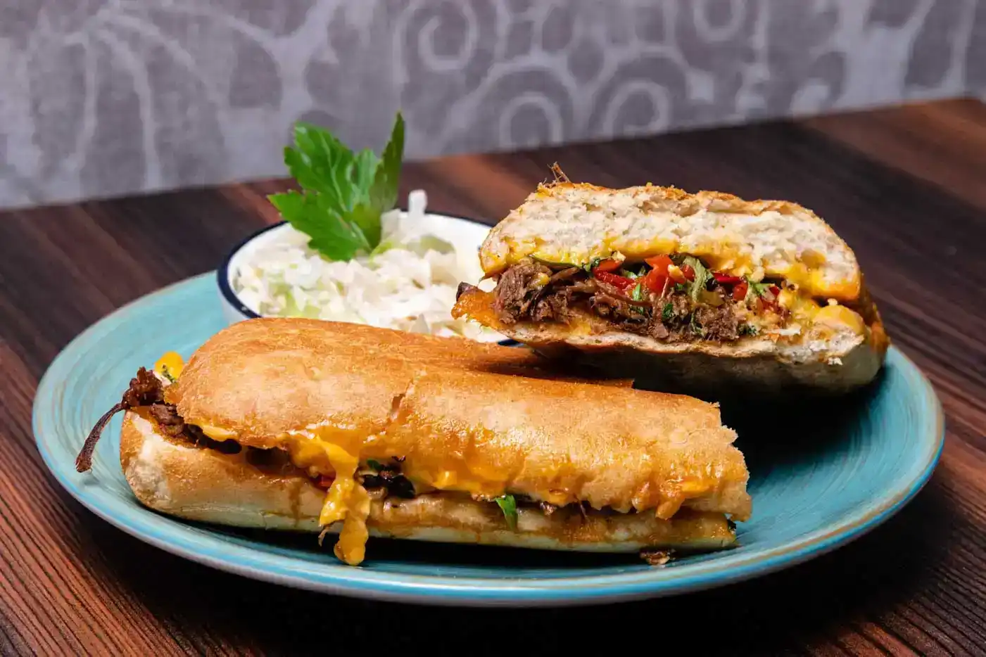 Zwei appetitliche Sandwiches mit Fleisch, Käse und Gemüse auf blauem Teller, professionelle Foodfotografie Wien