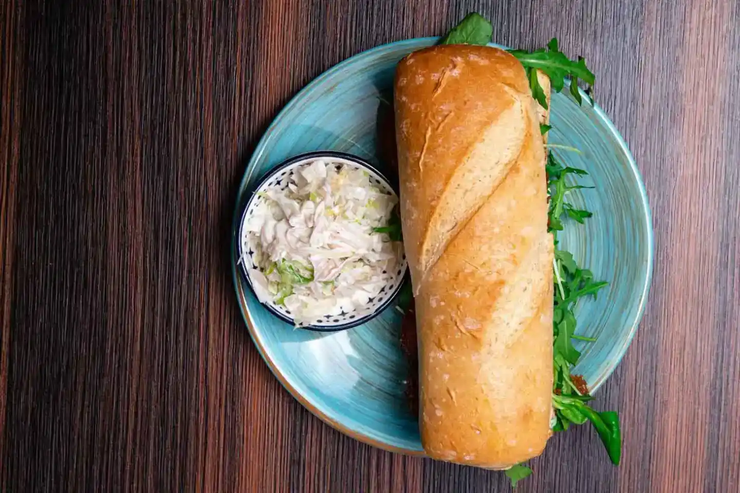 Knuspriges Baguette mit frischem Wildkräutersalat und cremiger Dip-Sauce auf blauem Teller - Foodfotografie Wien