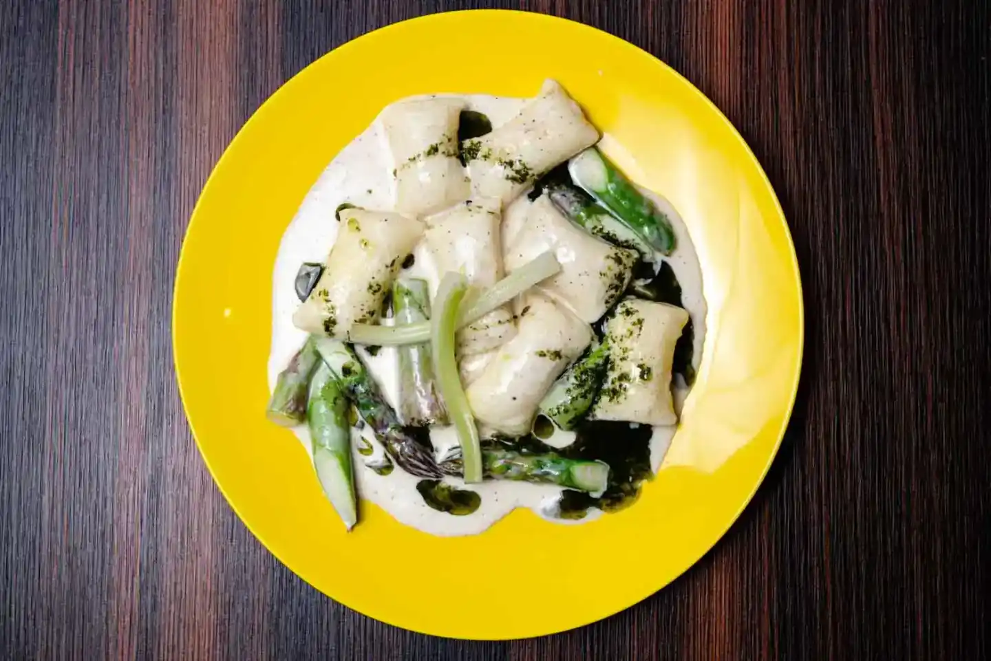 Gebratene Teigtaschen mit grünen Zwiebeln und Gewürzen auf gelbem Teller - professionelle Foodfotografie Wien