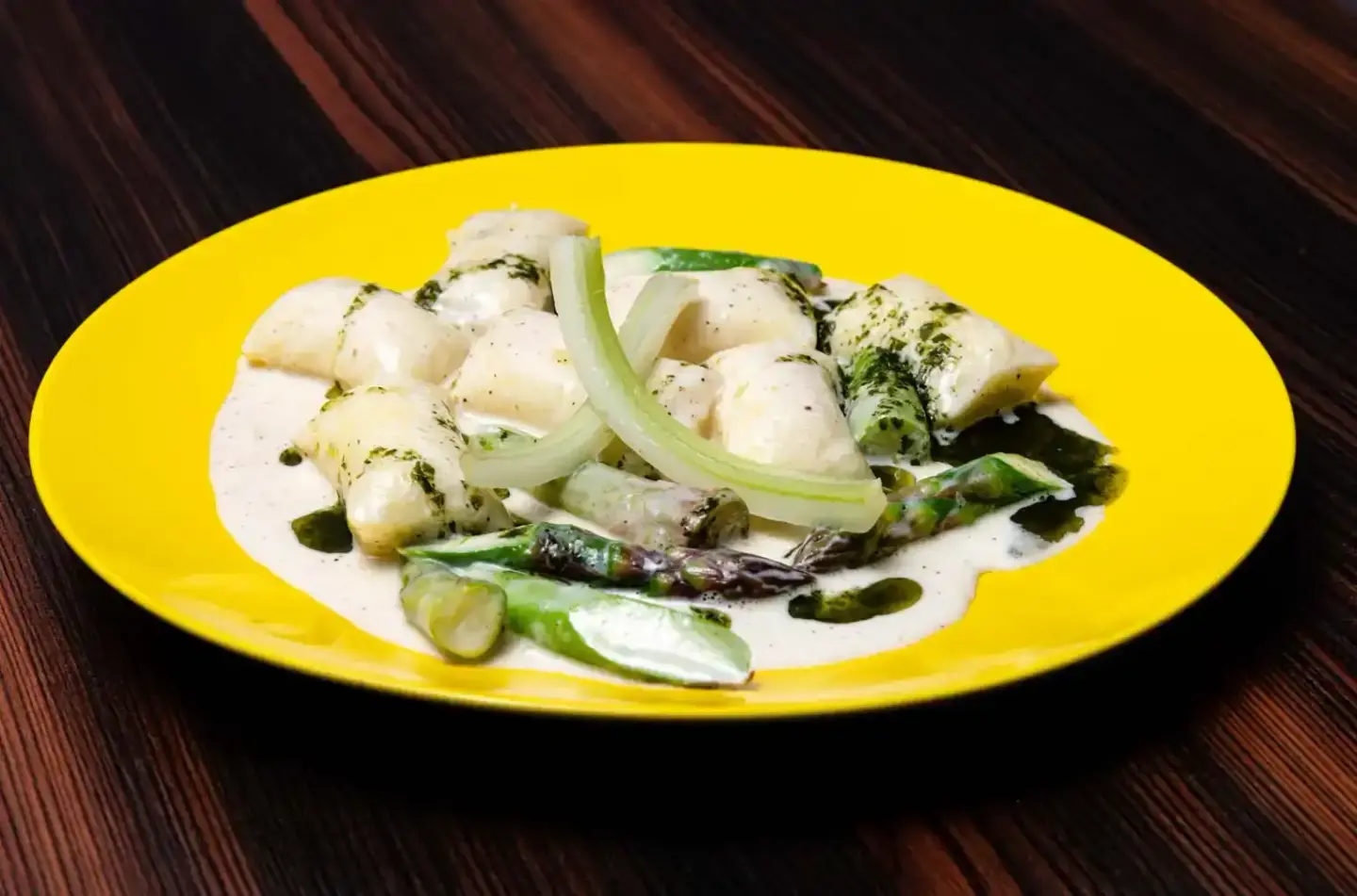 Elegantes Gericht mit Fischfilet, Spargel und cremiger Sauce auf gelbem Teller - Foodfotografie Wien