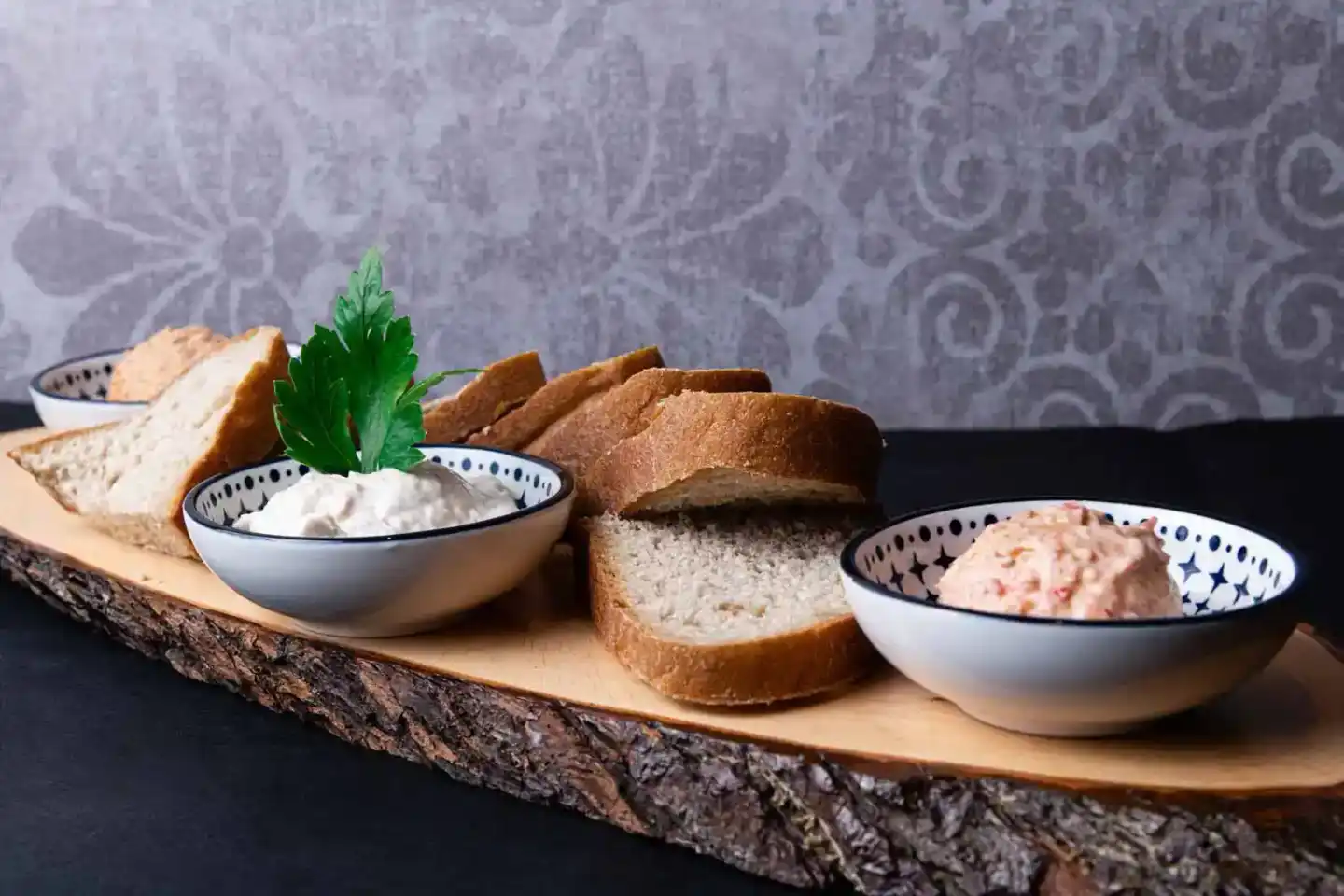 Appetitliche Brotscheiben mit Dips und Kräutergarnitur auf rustikalem Holzbrett - Foodfotografie Wien