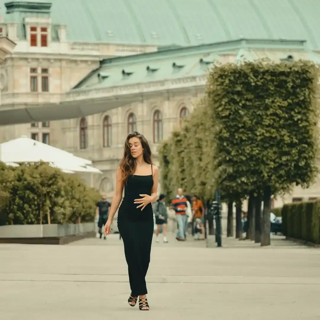 Junge Frau in schwarzem Kleid posiert elegant vor historischer Wiener Architektur während eines professionellen Portrait-Foto