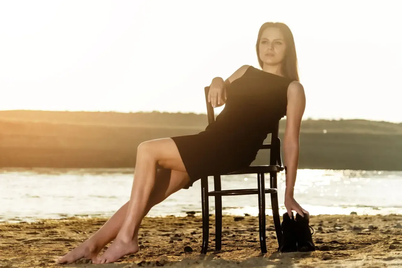 Frau sitzt entspannt auf Stuhl am Strand bei Sonnenuntergang – professionelles Portrait Wien