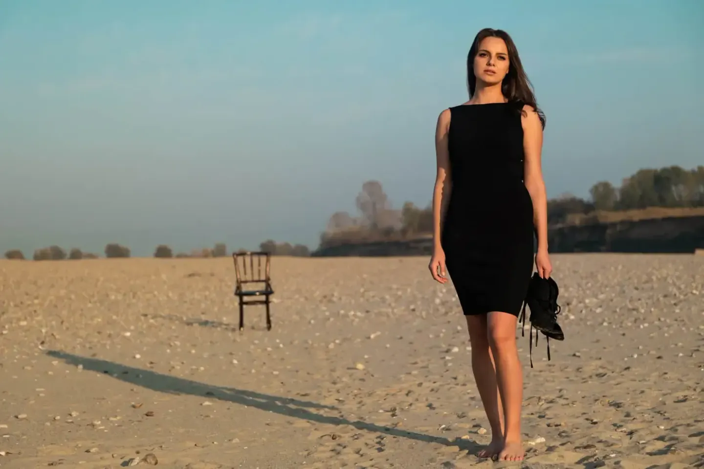 Junge Frau in schwarzem Kleid steht barfuß in einem weiten Feld, Portrait Wien mit minimalistischer Komposition