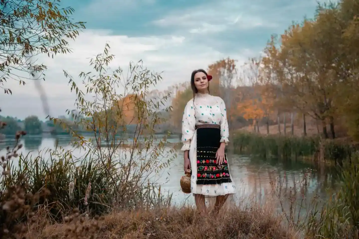 Frau in traditioneller Tracht am Flussufer, Portrait Wien mit Herbstlandschaft