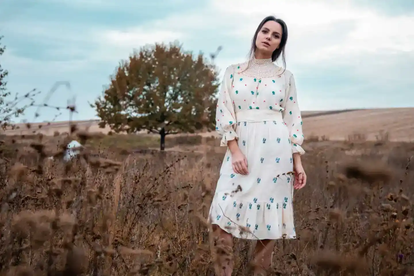 Porträt einer Frau in weißem Kleid mit Blumenmuster in einem herbstlichen Feld, professionelles Fotoshooting Wien