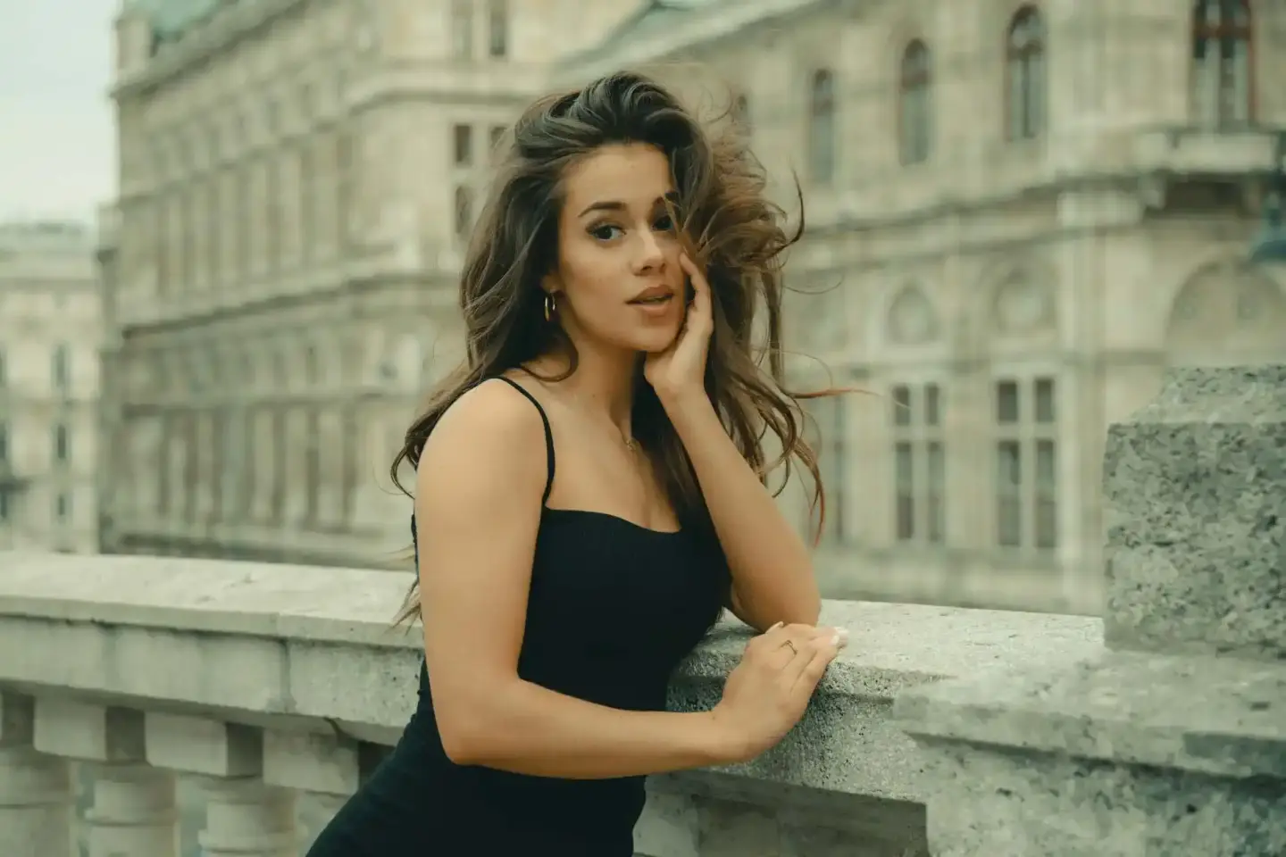 Elegantes Porträt einer Frau in schwarzem Top vor historischer Wiener Architektur