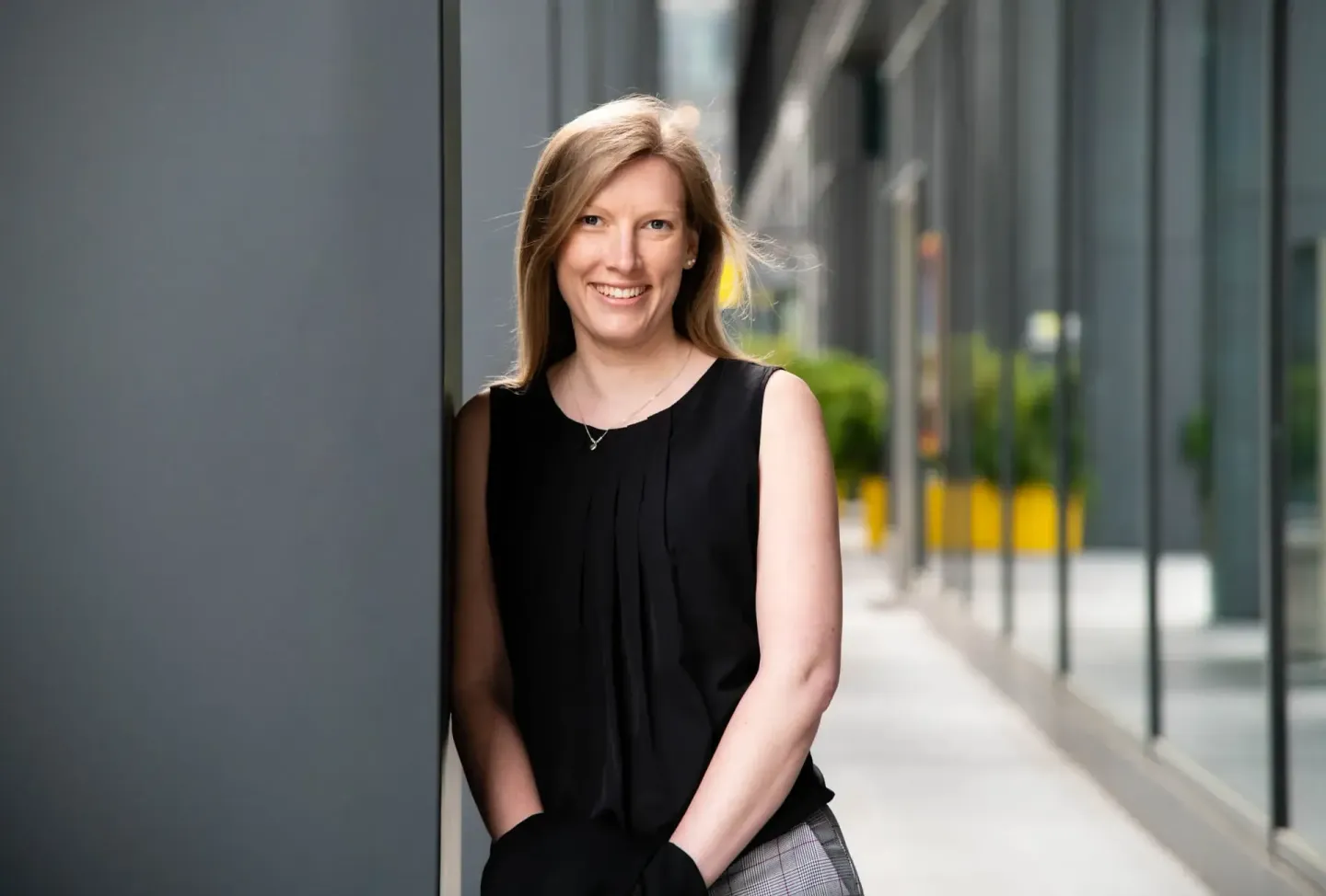 Lächelnde Frau in schwarzem Ärmelloses Top bei Outdoor-Portraitfotografie in Wien, urbane Architektur im Hintergrund
