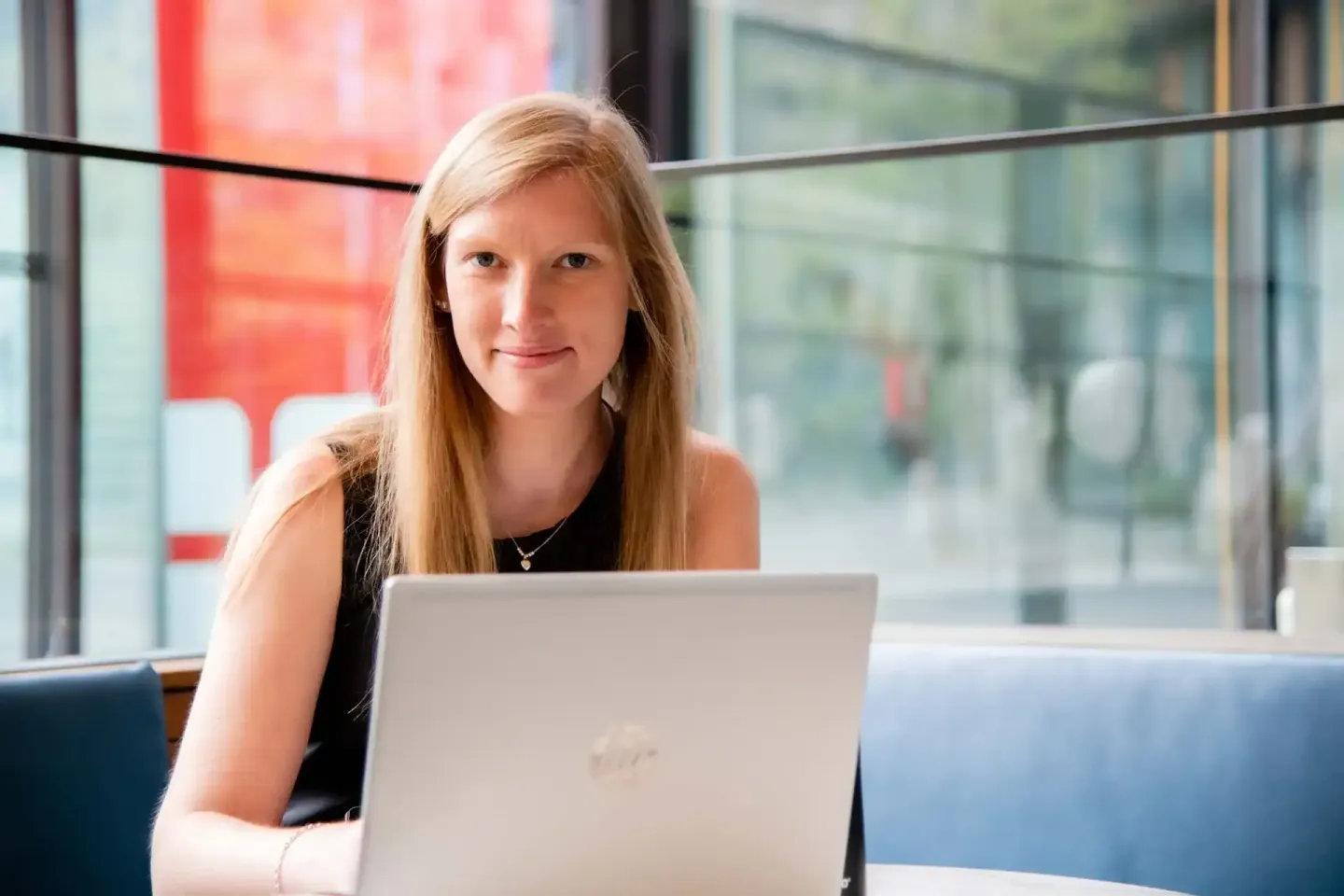 Junge Frau mit rötlichblondem Haar sitzt mit Laptop an Fenster, professionelles Portrait Wien