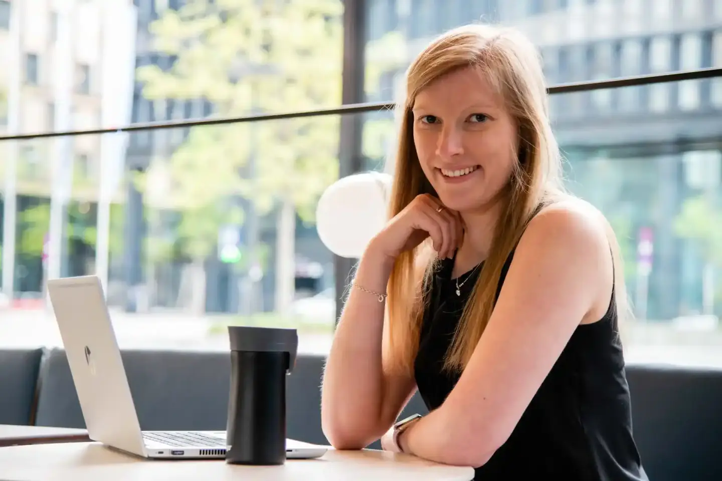 Professionelles Portrait einer Frau mit rötlich-blondem Haar an einem modernen Arbeitsplatz mit Stadtblick, aufgenommen von e