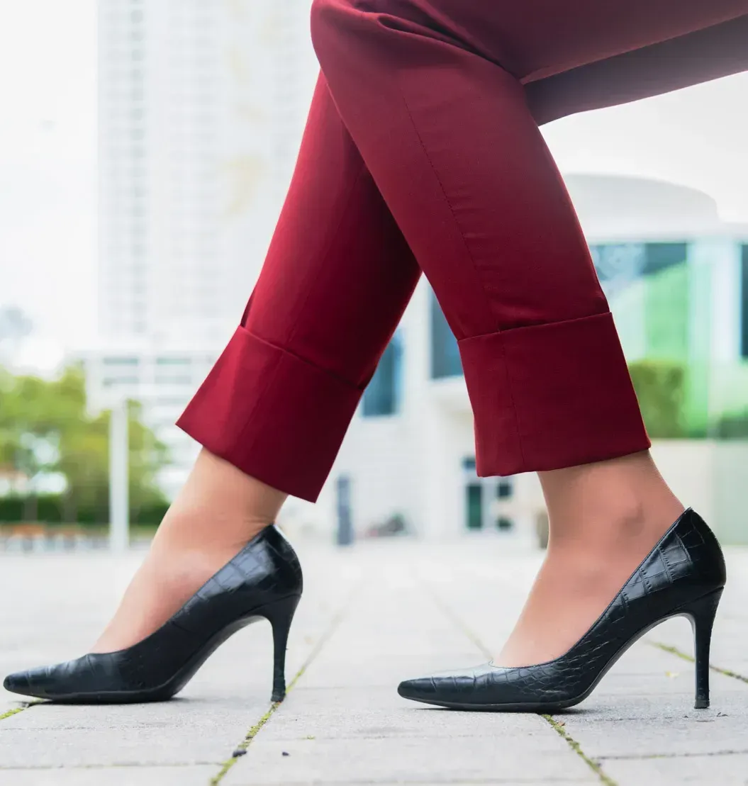 Frau in burgunderroten Cropped-Hosen und schwarzen Croc-Textil-Pumps auf Gehweg, Produktfotografie Wien