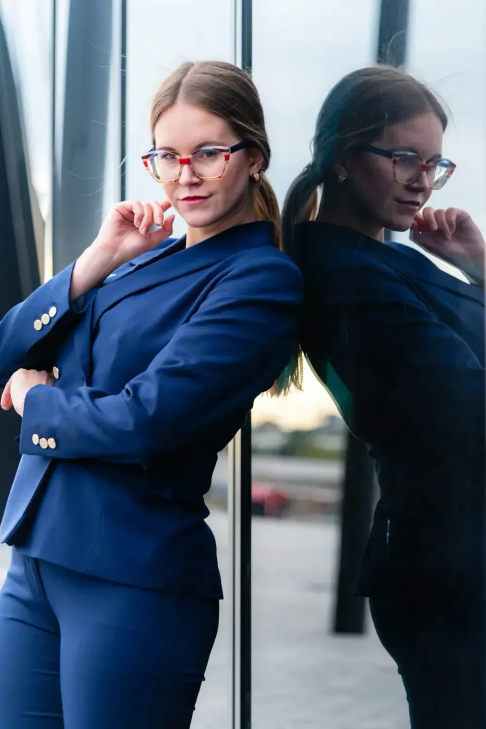 Zwei Frauen in professioneller Businesskleidung mit Brille posieren vor einer Glasfassade für Produktfotografie Wien