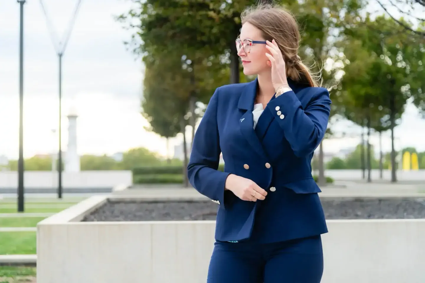 Geschäftsfrau in dunkelbauem Anzug mit Brille in einem modernen Park – Werbefotografie Wien