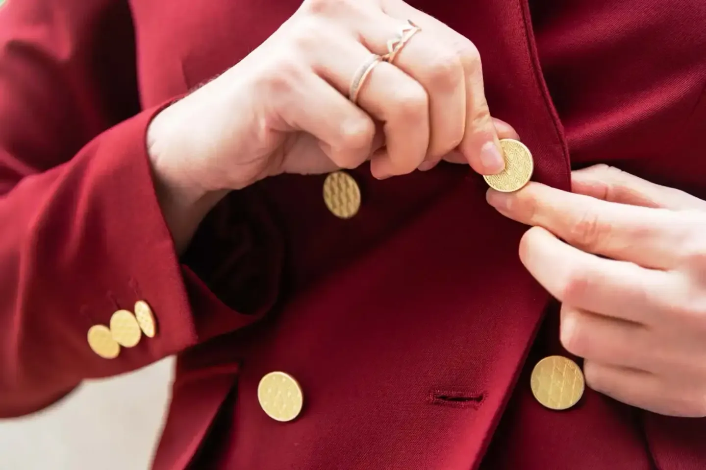 Detailaufnahme von goldenen Knöpfen an einem bordeauxroten Blazer, professionelle Produktfotografie Wien