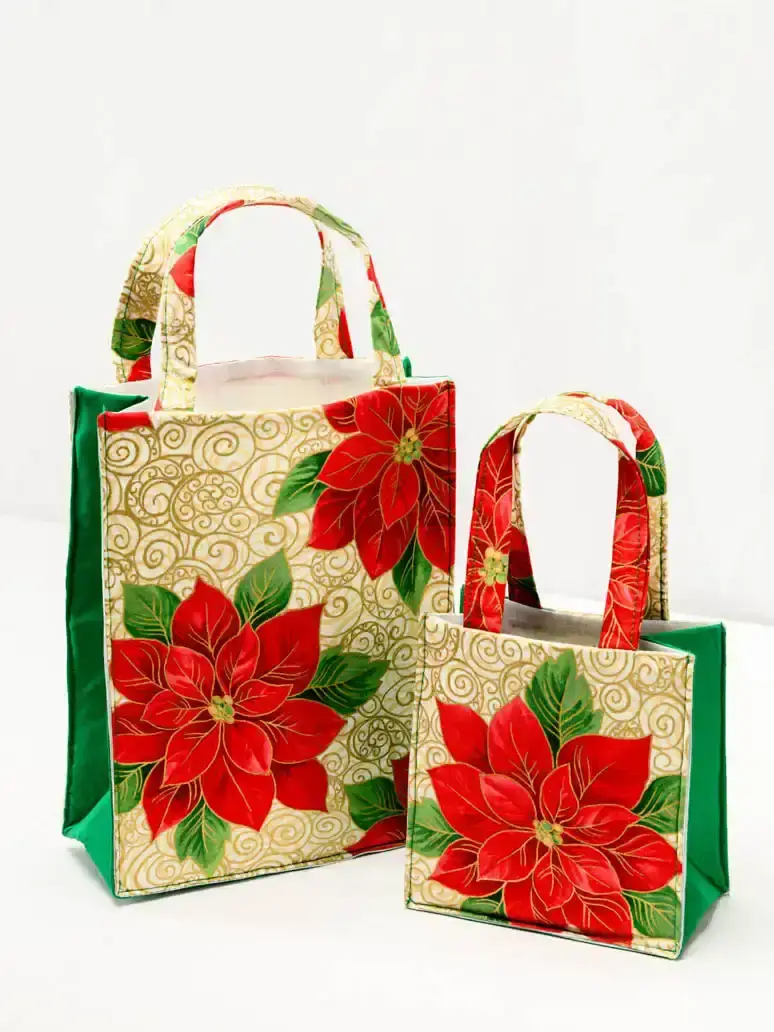 Zwei festliche Geschenktaschen mit roten Poinsettien und goldenem Muster - Produktfotografie Wien
