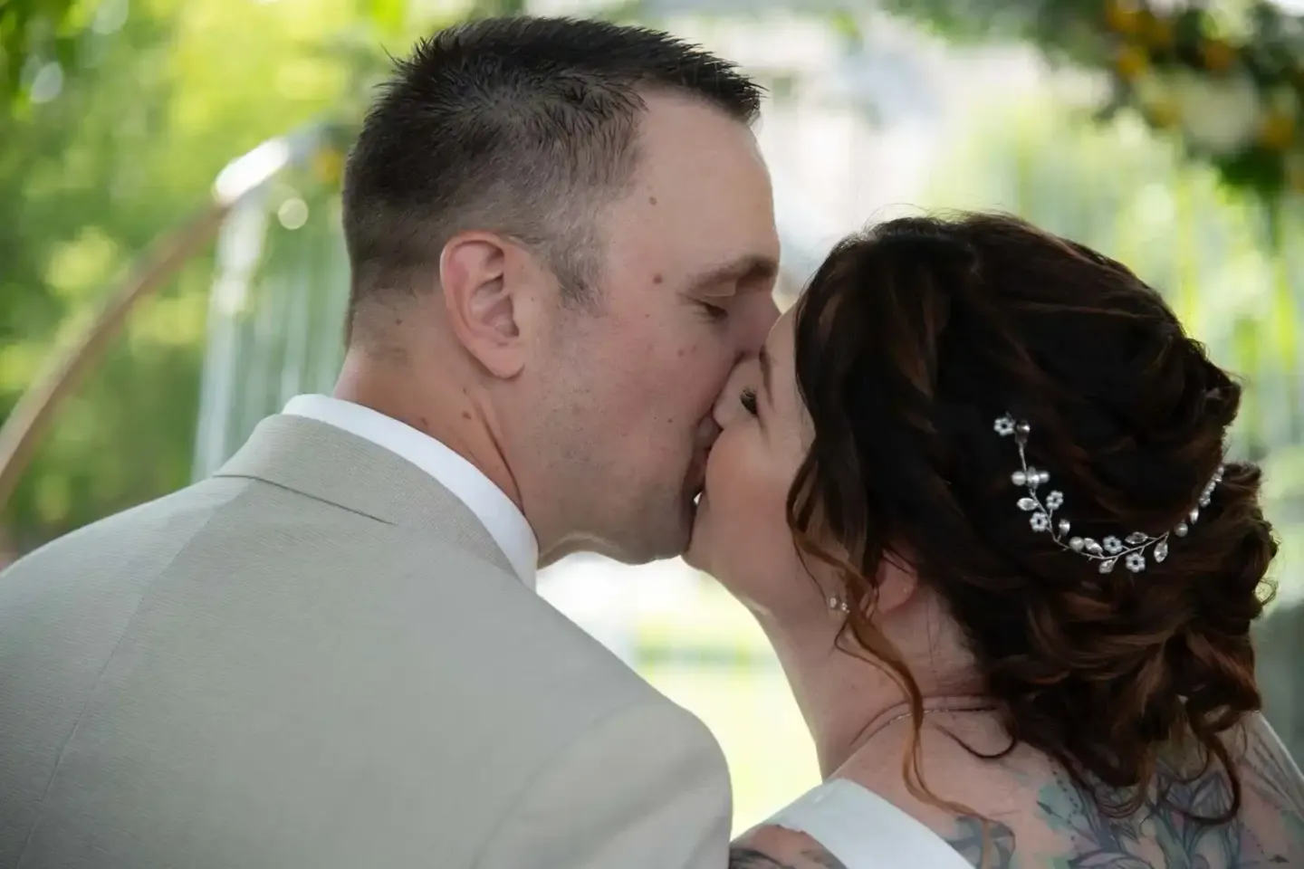 Brautpaar küsst sich unter grünem Blätterdach - professionelle Hochzeitsfotografie Wien