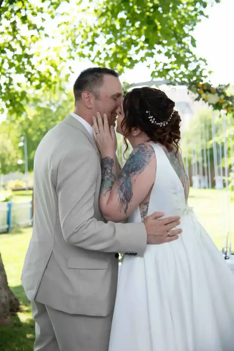 Brautpaar küsst sich unter grünem Blätterdach im Garten – professionelle Hochzeitsfotografie Wien