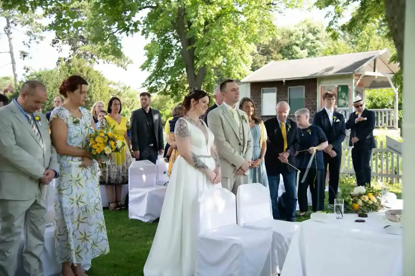 Brautpaar bei freier Trauung im Grünen, umgeben von Hochzeitsgästen unter Bäumen - Hochzeitsfotografie Wien