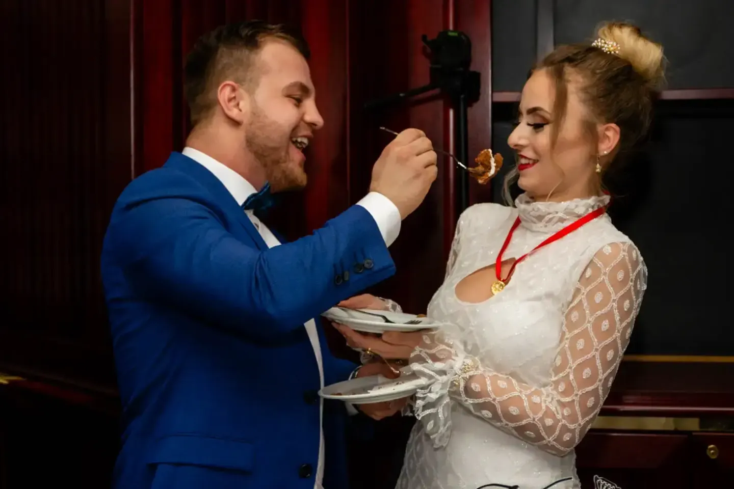 Brautpaar beim Anschneiden der Hochzeitstorte, festliches Hochzeitsfoto Wien mit Bräutigam im blauen Anzug und Braut im weiße