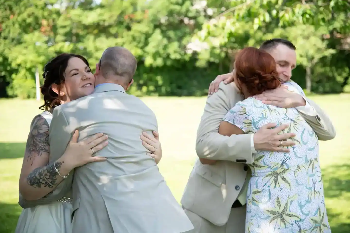 Brautpaar umarmt Familienmitglieder bei einer Hochzeit im Freien, Hochzeitsfotografie Wien
