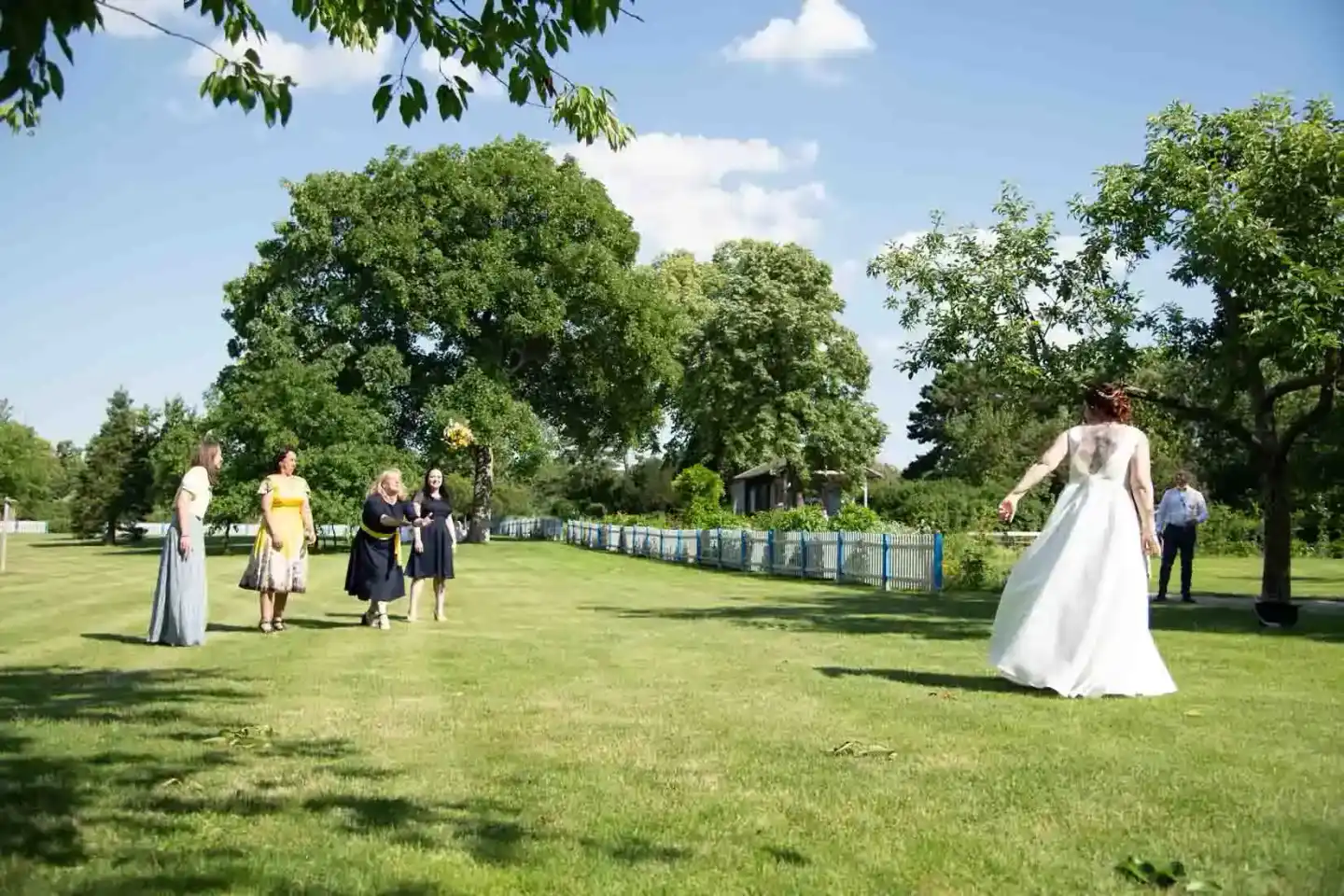 Braut in weißem Hochzeitskleid auf grüner Wiese mit Gästen, Hochzeitsfotograf Wien dokumentiert den Moment
