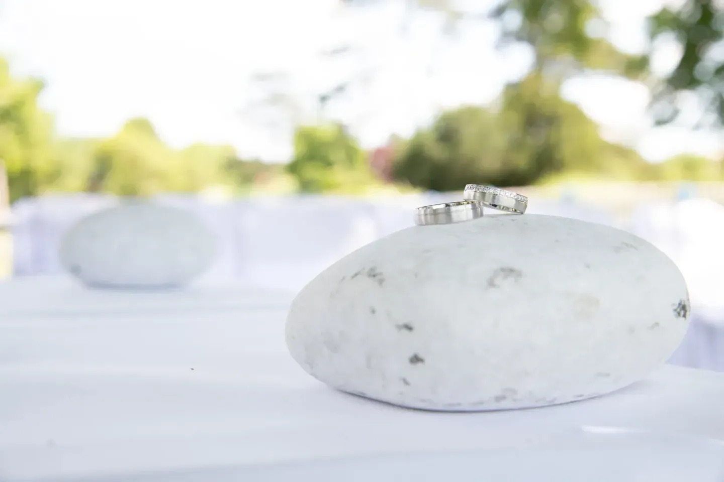 Zwei silberne Trauringe liegen auf einem weißen Stein bei einer Hochzeitsfotografie in Wien
